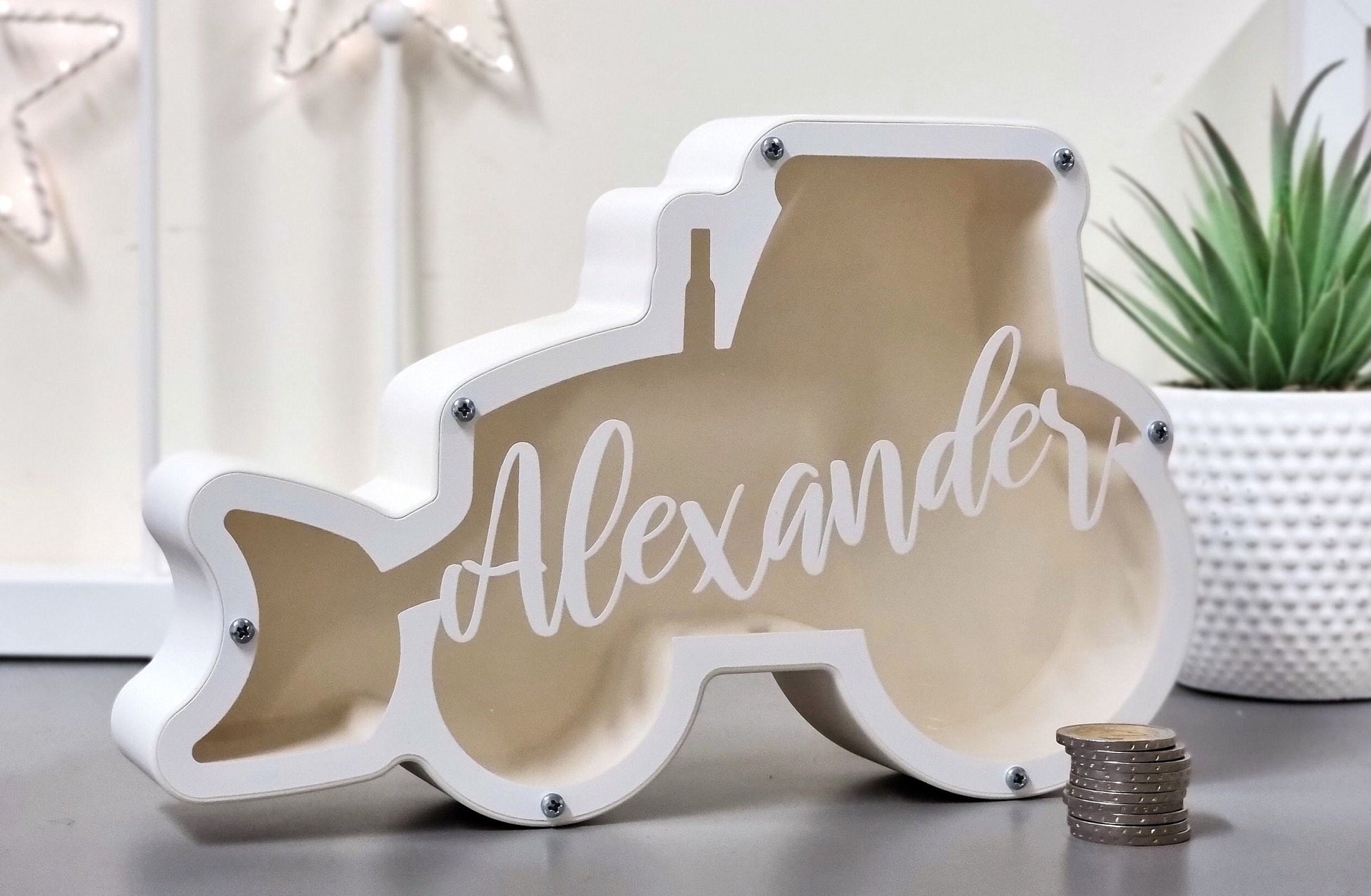 Bulldozer-shaped personalized piggy bank on a table with a plant, great for kids' rooms.