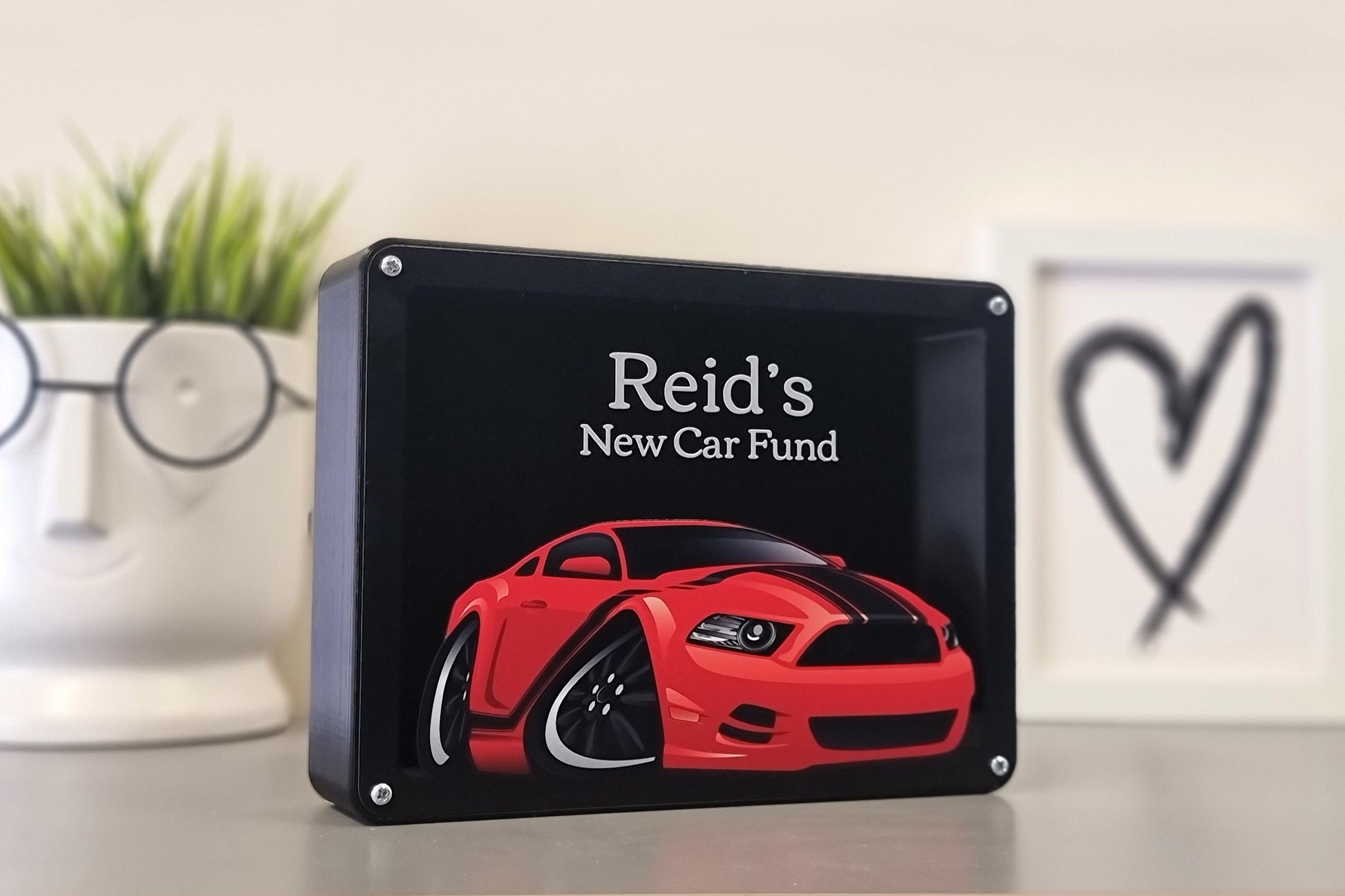 Personalized car piggy bank with the name Reid, featuring car designs, ideal gift for car enthusiasts.