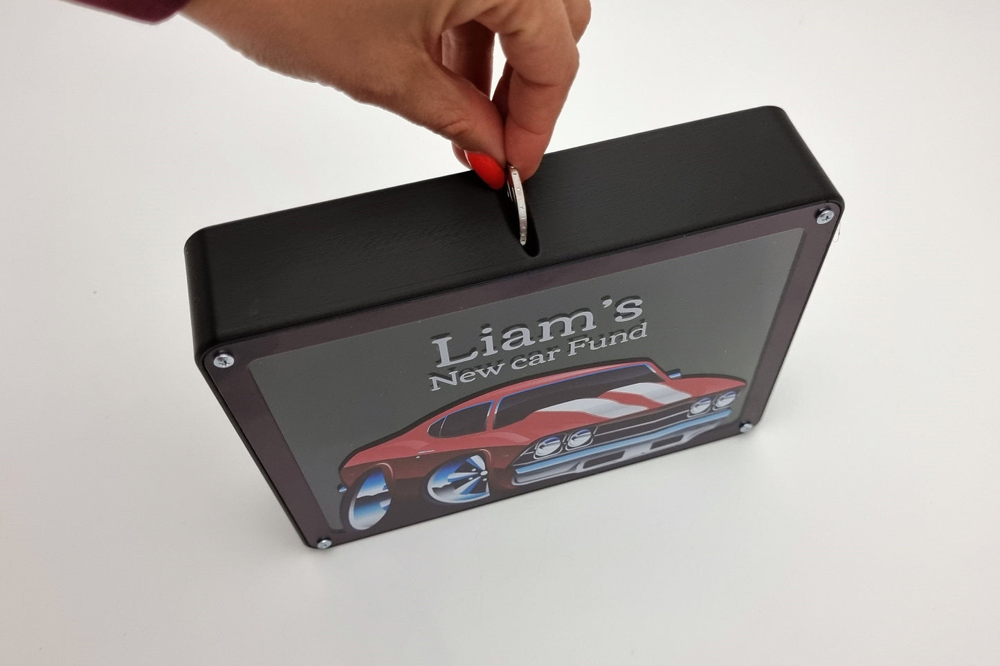 Removing the back cover of a personalized red car piggy bank to access savings